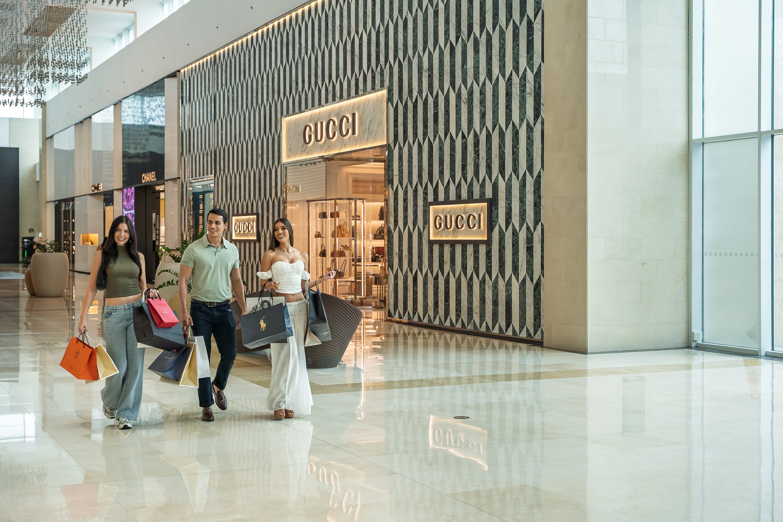 Grupo de jóvenes con bolsas de compras de marcas exclusivas caminando frente a tienda Gucci, fotografía lifestyle de lujo en Centroamérica por Gatopardo Media.