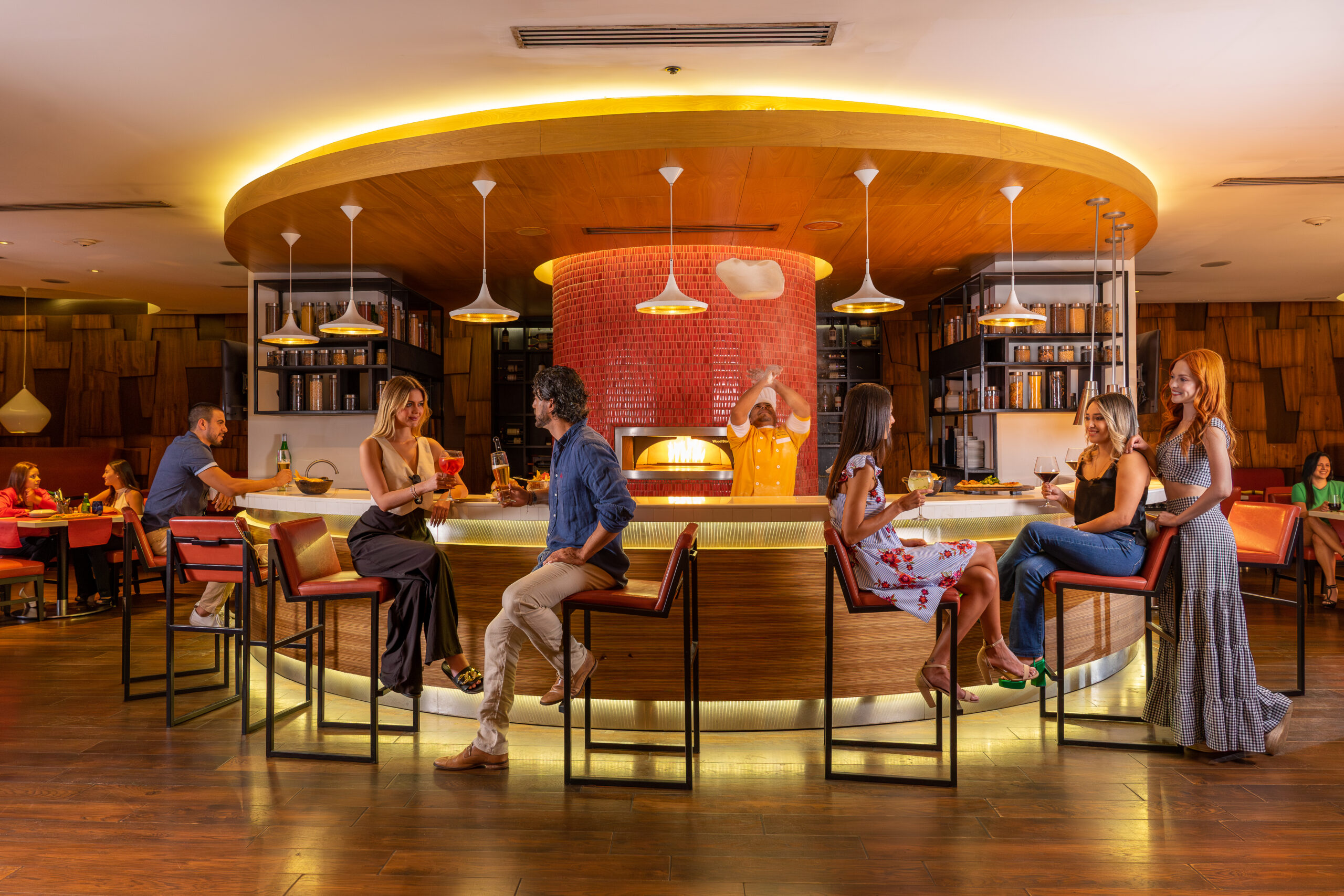 Barra iluminada de restaurante con clientes disfrutando cócteles.