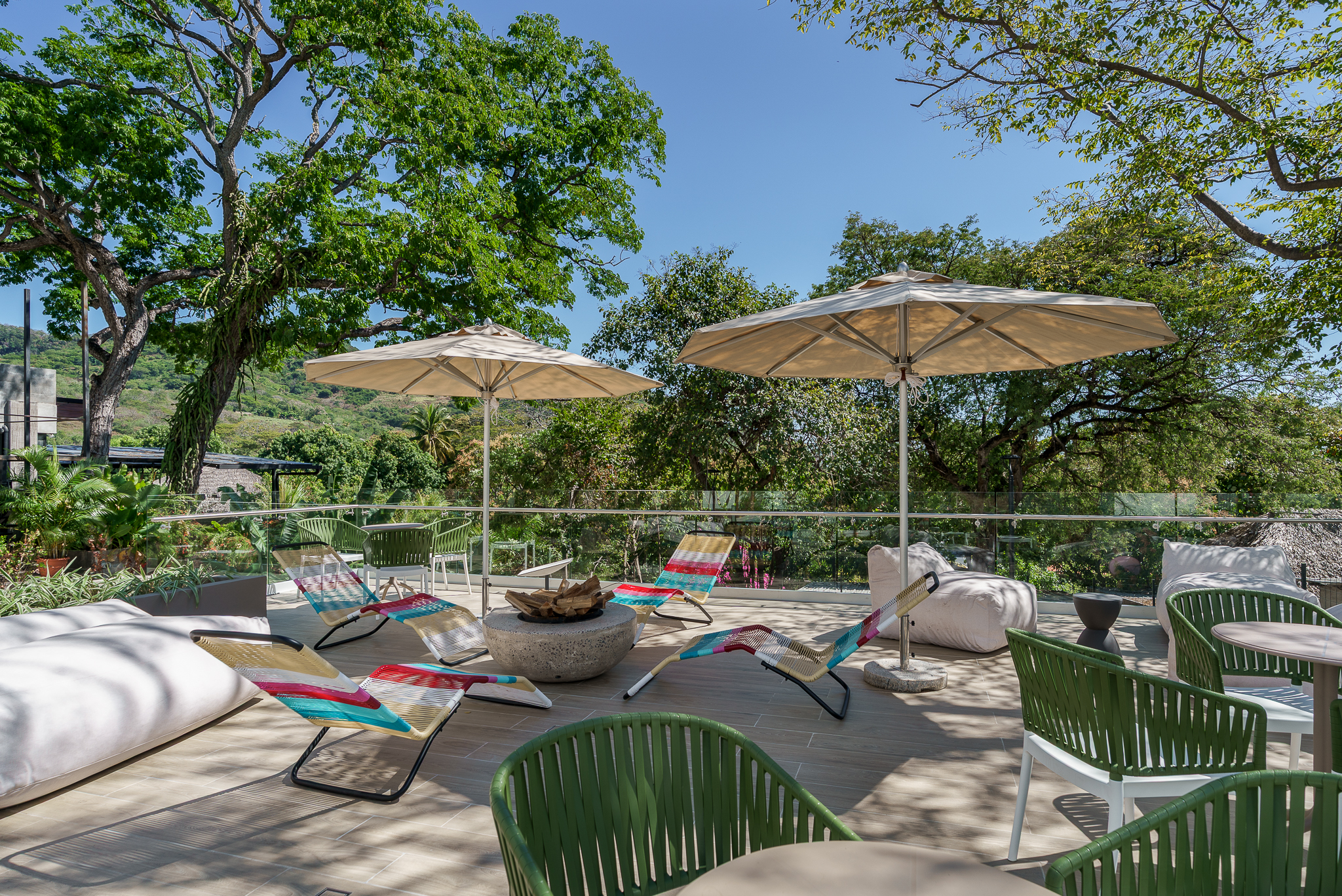 Open-air terrace with parasols, colourful chairs and a view onto nature.