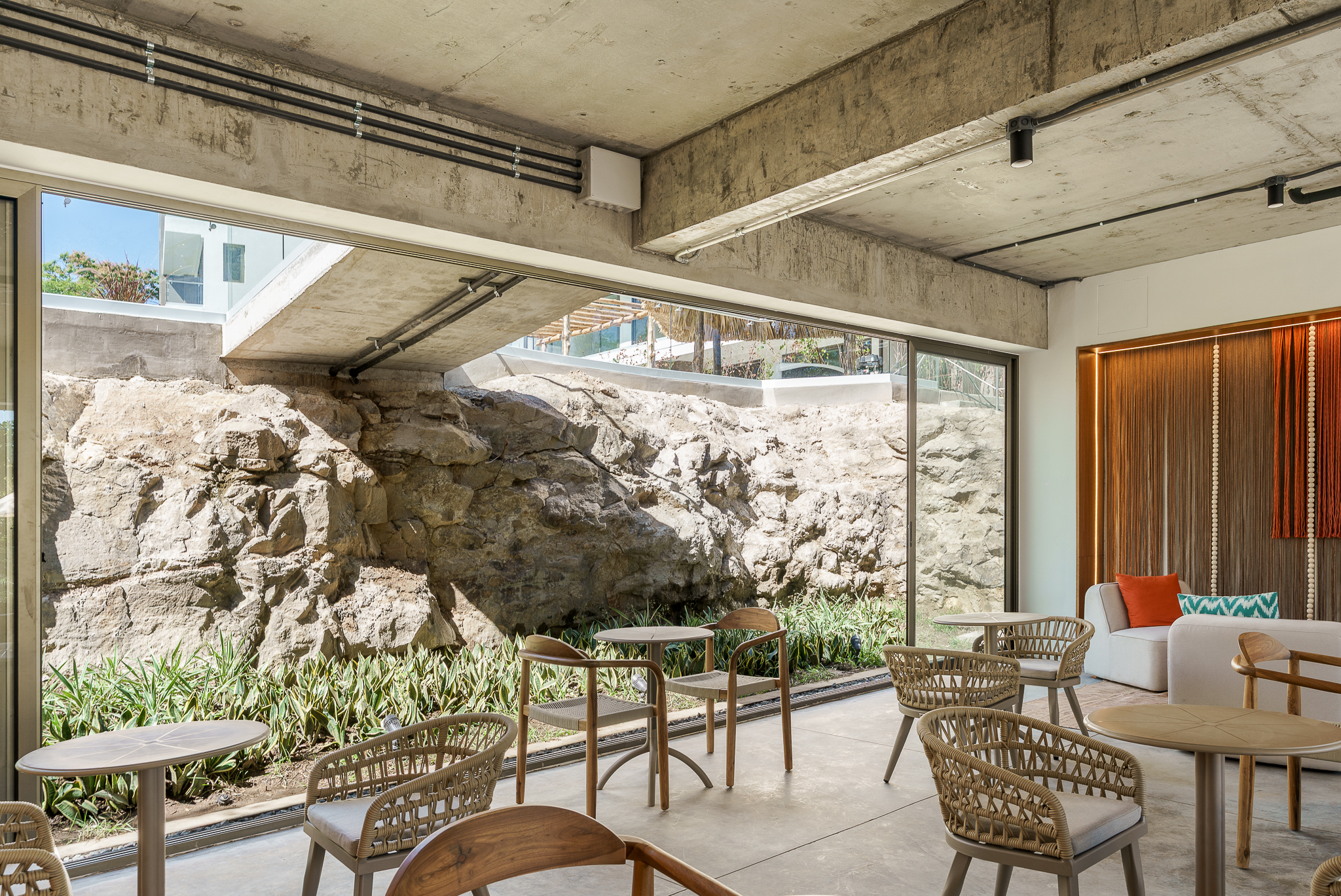 Minimalist interior with exposed stone and wooden tables.