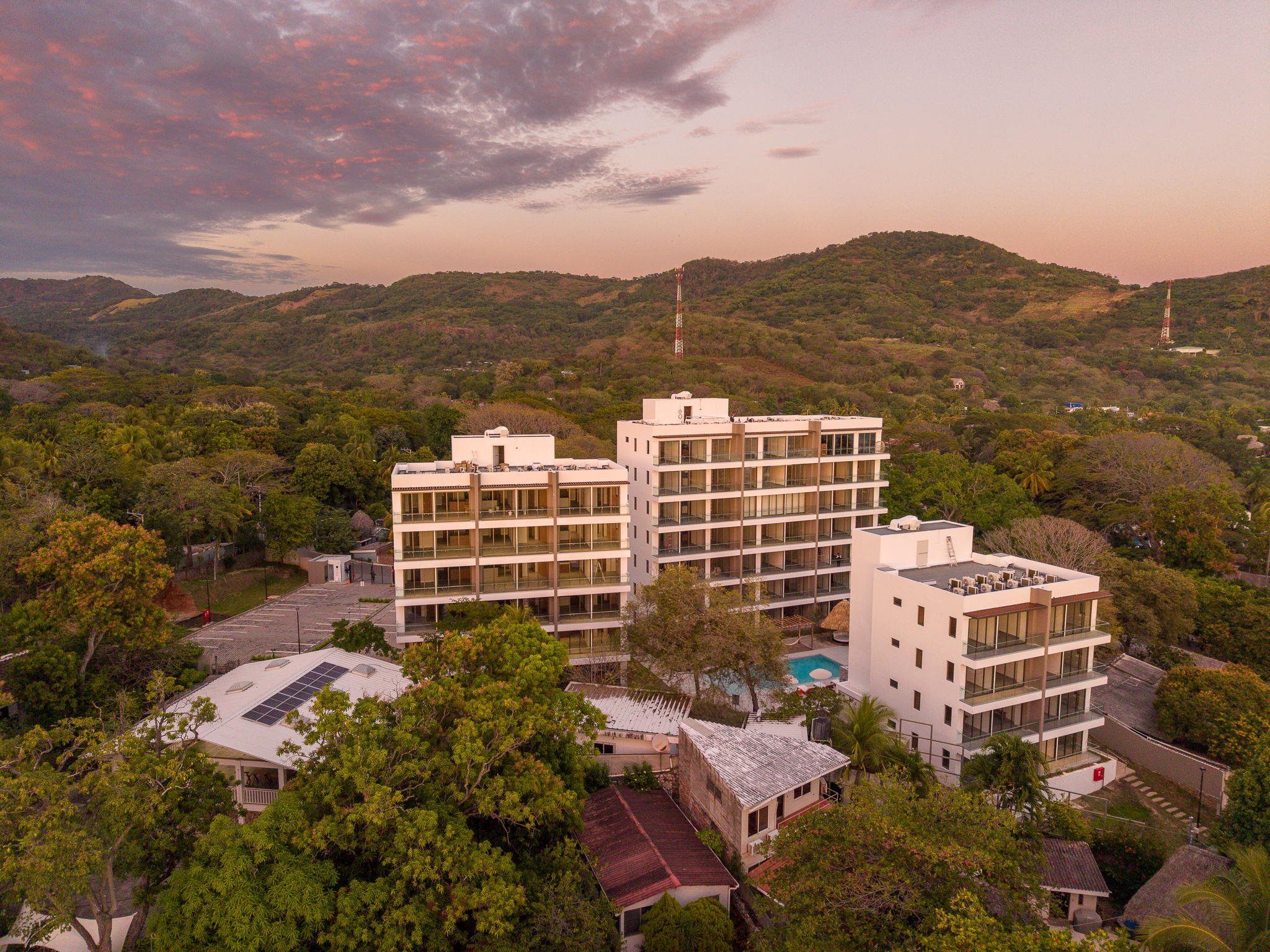 Vista aérea de un desarrollo residencial moderno rodeado de árboles y montañas.